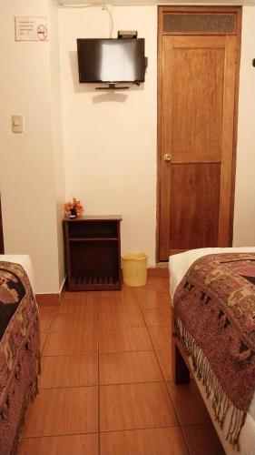 a room with two beds and a television on the wall at Catari's House in Machu Picchu