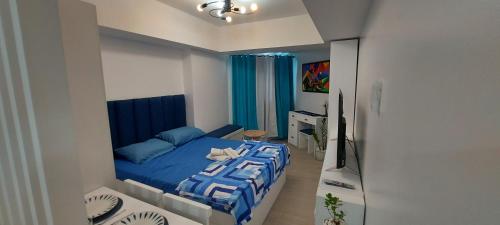 a bedroom with a blue bed and a television at Azure North San Fernando Pampanga in San Fernando