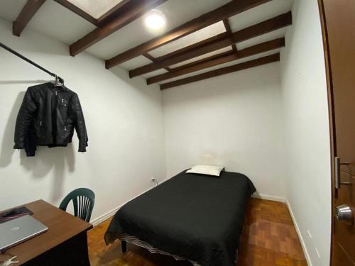 Cette chambre comprend un lit et une veste accrochée au mur. dans l'établissement La Casa de Lu Los Rosales, à Manizales