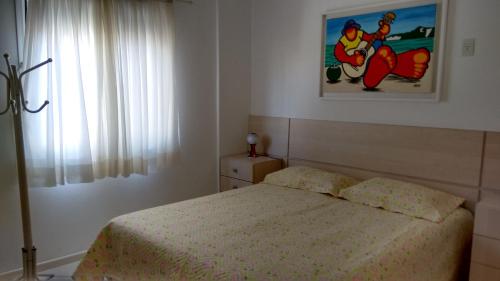 een slaapkamer met een bed en een foto aan de muur bij Residencial Ilha Verde (201) in Florianópolis