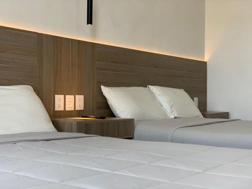 una camera con due letti con lenzuola bianche di Hotel Blanco Pachuca a Pachuca de Soto