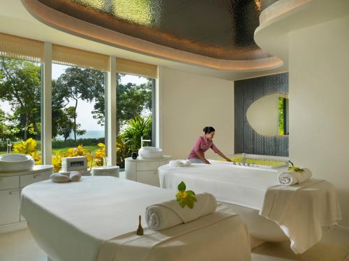 a woman standing in a room with two beds at The ShellSea Krabi I Luxury Beach Front Resort & Pool Villa in Ao Nam Mao