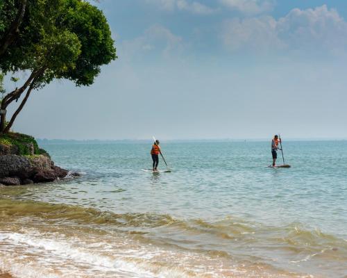 two people on paddle boards in the water on the beach at The ShellSea Krabi I Luxury Beach Front Resort & Pool Villa in Ao Nam Mao