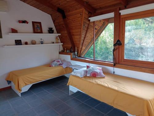 two beds in a room with two windows at loft interno in Villa General Belgrano