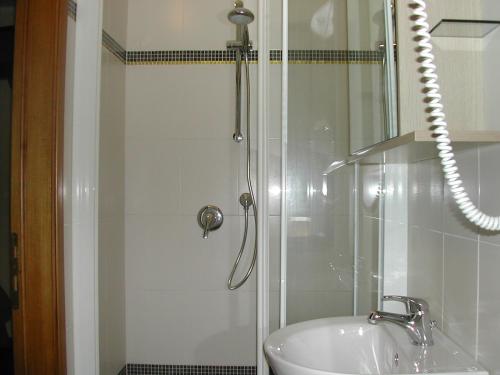 y baño con ducha y lavamanos. en Hotel Flora, en Marina di Bibbona
