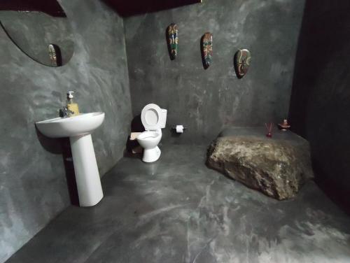 a bathroom with a sink and a toilet and a rock at Hotel Jasayma dentro del Parque Tayrona in El Zaino