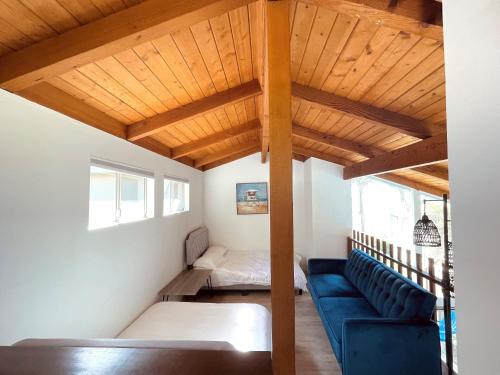 a living room with a blue couch and a bed at OCEAN FRONT Beach HOUSE! Private Stairs to SAND! in Laguna Beach