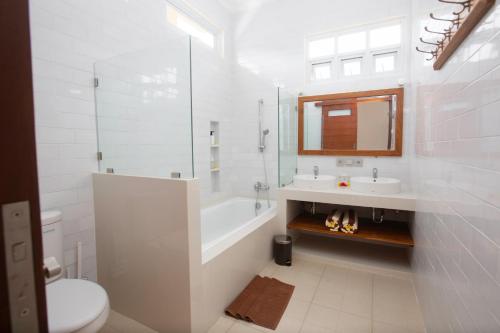 a bathroom with a tub and a sink and a toilet at Donguri House Bali in Jimbaran