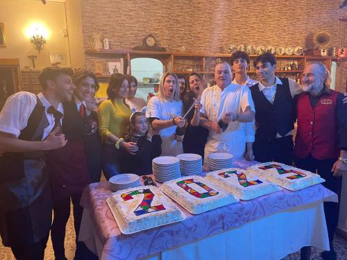 um grupo de pessoas à volta de uma mesa com dois bolos em Albergo Ristorante Giuliana em Guarcino
