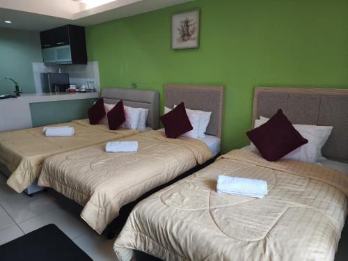 deux lits dans une chambre aux murs verts dans l'établissement The Viana Apartment V, à Kota Bharu