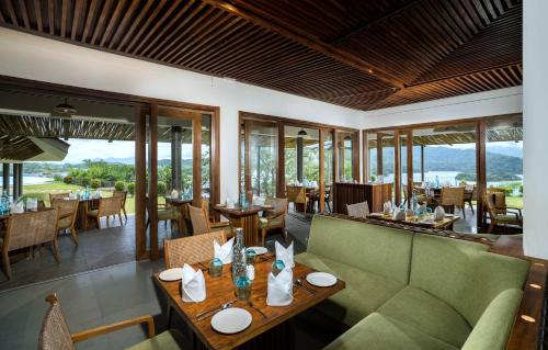 a restaurant with a green couch and tables and chairs at MOUNTAIN SHADOWS RESORT Wayanad in Wayanad