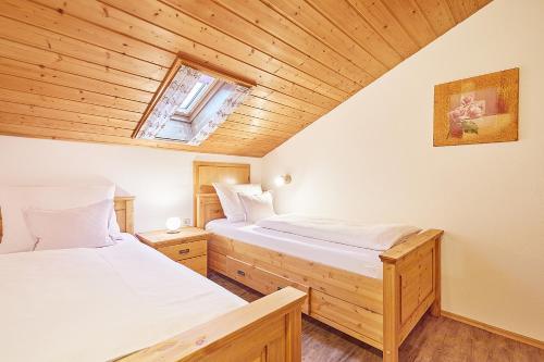 two beds in a room with wooden ceilings at Haus Kohlpointner in Oberwössen