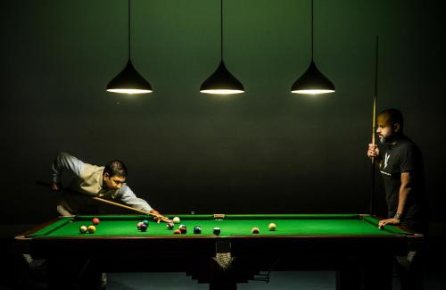 two men playing a game of pool on a pool table at MOUNTAIN SHADOWS RESORT Wayanad in Wayanad