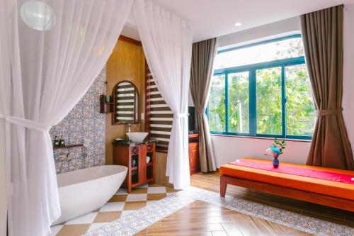 a bathroom with a tub and a large window at De'Colore Villa Hoi An in Hoi An