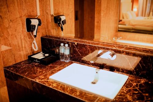 a bathroom with a sink and two phones on the wall at Portola Grand Renggali Hotel Takengon in Takengon