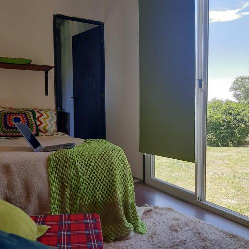 a bedroom with a bed and a window with a laptop on it at CASA CONTAINER BOSQUE Y MAR in Mar del Plata