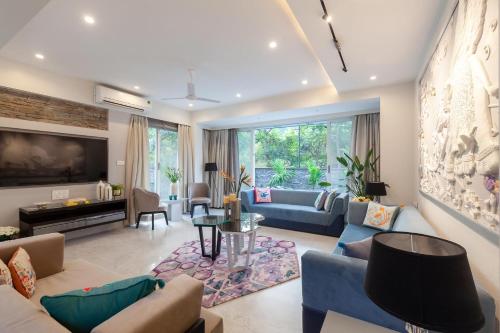 a living room with blue couches and a tv at StayVista's Le Sutra Great Escapes - Udaan - Artistic Rooms, Terrace Jacuzzi with Scenic View in Lonavala