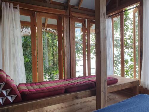 a room with a window with red cushions on a bench at Palm Beach Resort Koh Phayam in Ko Phayam