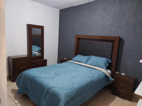 a bedroom with a blue bed and a mirror at Casa Camichines in Ciudad Guzmán