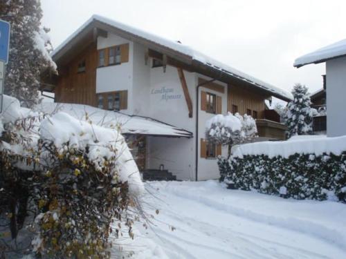 ein Haus mit Schnee auf dem Boden davor in der Unterkunft Landhaus Alpensee in Oberstdorf