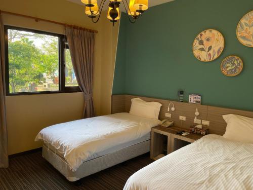 Cette chambre comprend 2 lits et une fenêtre. dans l'établissement Breeze and Waves Hostel, à Jinning