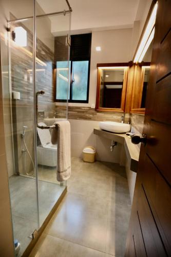a bathroom with a glass shower and a sink at Hidden relaxation at Kings residence in Kandy