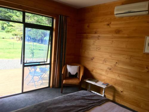 a bedroom with a bed and a chair and a window at Off the Beaten Track B&B in Canvastown