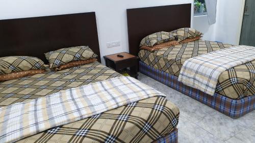 Zimmer mit 2 Betten und einem Nachttisch in der Unterkunft CHILY GUESTHOUSE LANGKAWI in Pantai Cenang