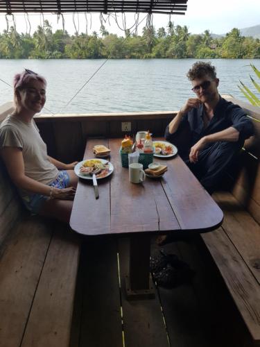 a man and woman sitting at a table in a boat at The Hideaway in Kampot