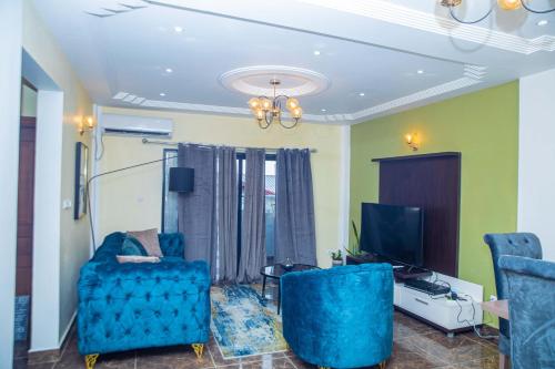 uma sala de estar com cadeiras azuis e uma televisão em Résidence Fé em Douala
