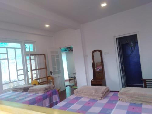 a room with two beds and a rug on the floor at Forest Cyniciam Homestay in Ohiya