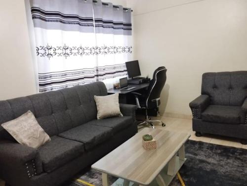 a living room with a couch and a desk at 2 BR, TreasureTree Homes, Thika. in Thika