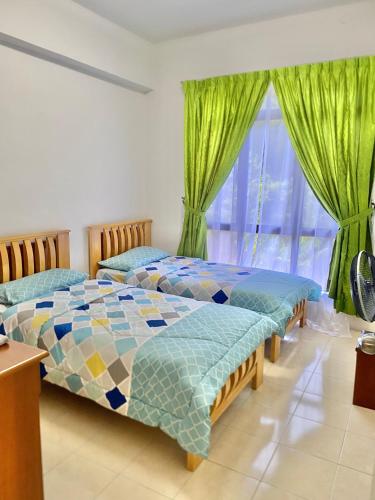 two beds in a room with green curtains at Homestay Legacy Kamariah Ahmad,Lumut in Lumut