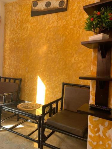 a room with two chairs and a table and a yellow wall at Cuartos kukulcan in Valladolid