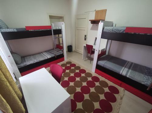 a room with two bunk beds with a table and a rug at Hostelida Konya in Konya