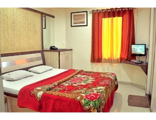 a bedroom with a bed with a red blanket at Hotel Pearl,Indore in Indore