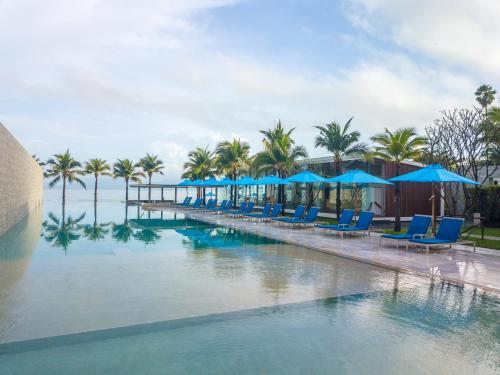 a pool at a resort with blue chairs and umbrellas at Explorar Koh Samui - Adults Only Resort and Spa in Mae Nam