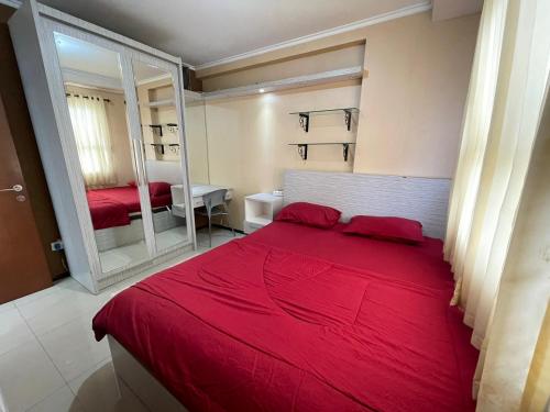 Schlafzimmer mit einem roten Bett und einem Spiegel in der Unterkunft 2BR Gateway Pasteur Apartment in Bandung