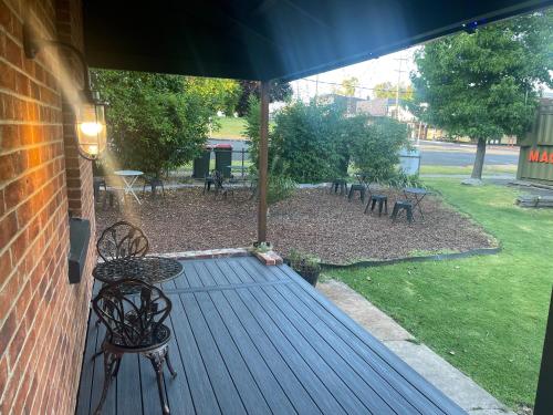 una terraza al aire libre con sillas, mesas y sombrilla en Riders’ Rest Nundle en Nundle