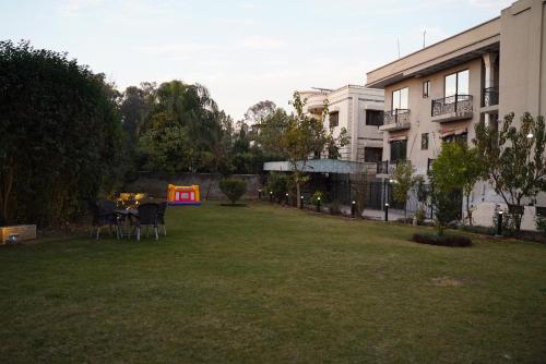 un cortile con tavolo, sedie e un edificio di La Maison Islamabad a Islamabad