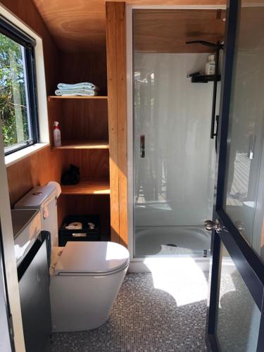 a small bathroom with a toilet and a shower at Kākā Ridge Retreat Bush Hideaway in Tawharanui