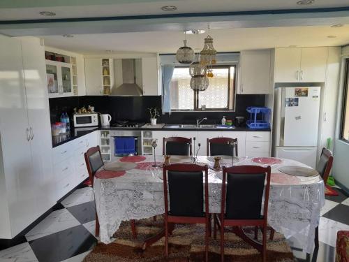 eine Küche mit einem Tisch und Stühlen sowie eine Küche mit weißen Schränken in der Unterkunft Karans Apartment 