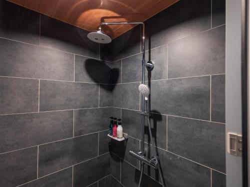a bathroom with a shower with black tiles at Atami Onsen Yamaki Ryokan in Atami