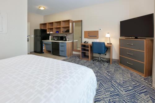 a hotel room with a bed and a desk and a television at Candlewood Suites Idaho Falls by IHG in Idaho Falls