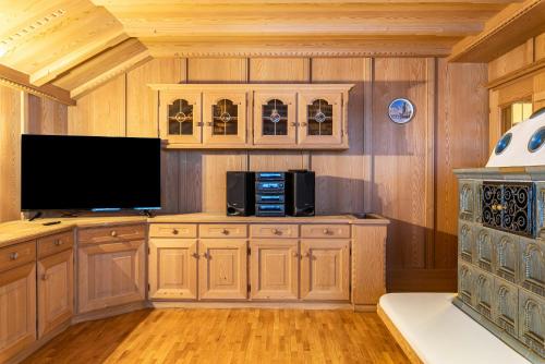 Apartment Christian في أورتيساي: مطبخ مع خزائن خشبية وتلفزيون بشاشة مسطحة