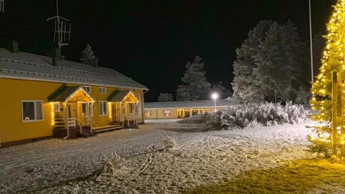 a building with a christmas tree in front of it at night at Wilderness Estate Pukari, Kuusamon Erämajoitus in Kuusamo