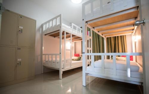 two white bunk beds in a room with a closet at DKaYa Hostel in Khao Lak