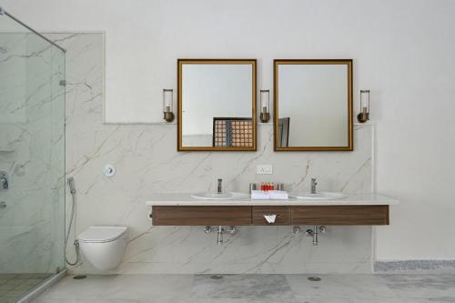 a bathroom with two sinks and a toilet and mirrors at Fateh Vilas by Fateh Collection in Udaipur