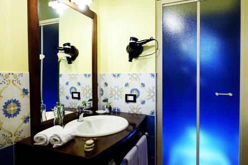 uma casa de banho com um lavatório e um chuveiro com um espelho. em Agriturismo Montalbano em Cartabubbo