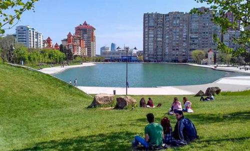 a group of people sitting in the grass near a lake at CHEMPION HOSTEL BAKU in Baku